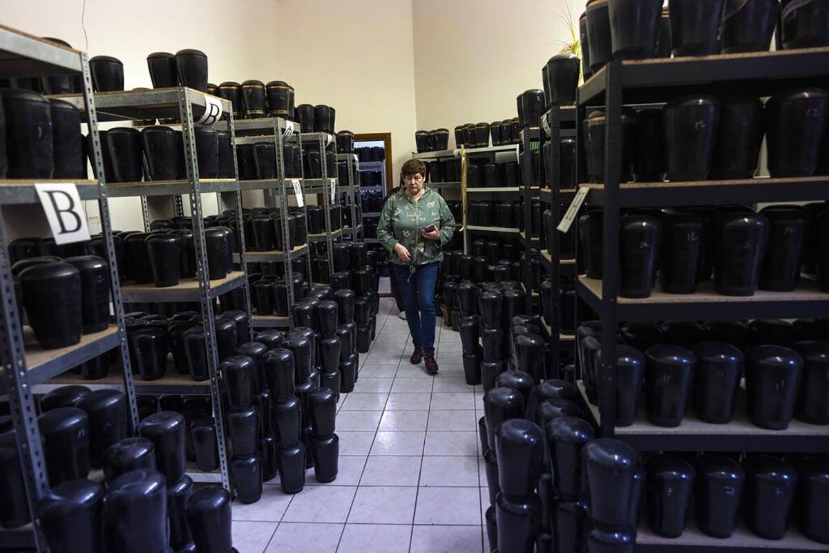 A cemetery worker walks amid marble urns that contains the cremated remains of people inside Ba ...