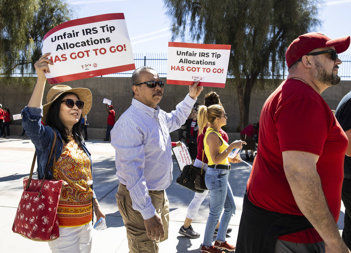 Nanivanh Phongsavath, left, holds a sign in support of her husband Mike, a bartender at Luxor, ...