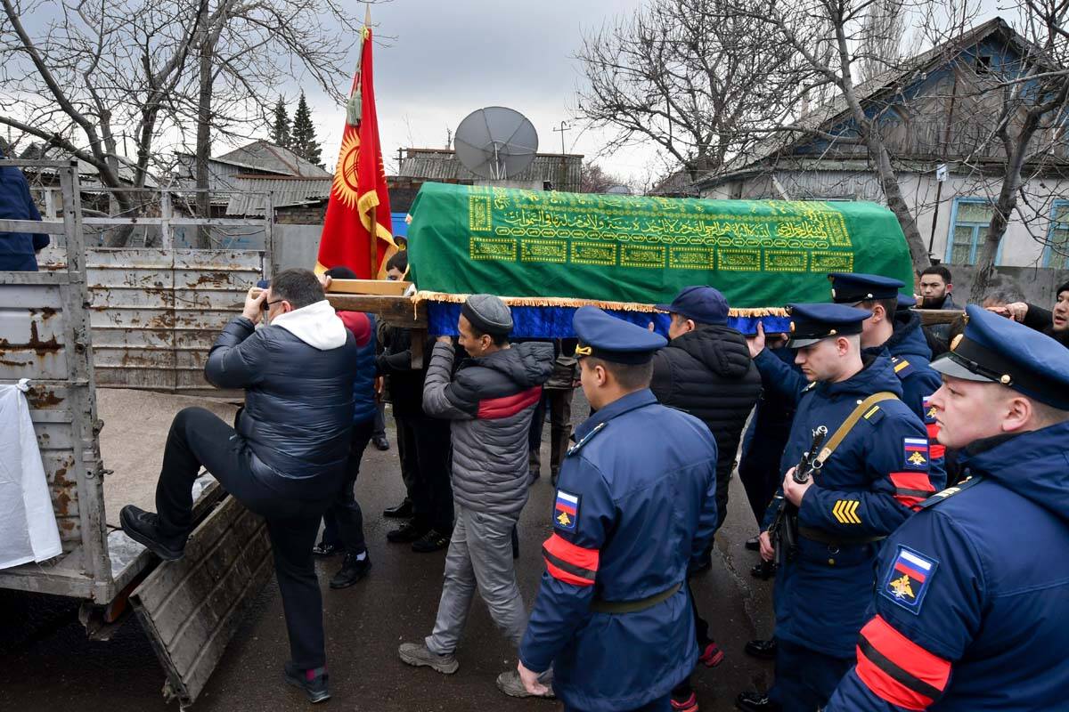 Russian servicemen stand next as people load a coffin with the body of Russian Army soldier Rus ...