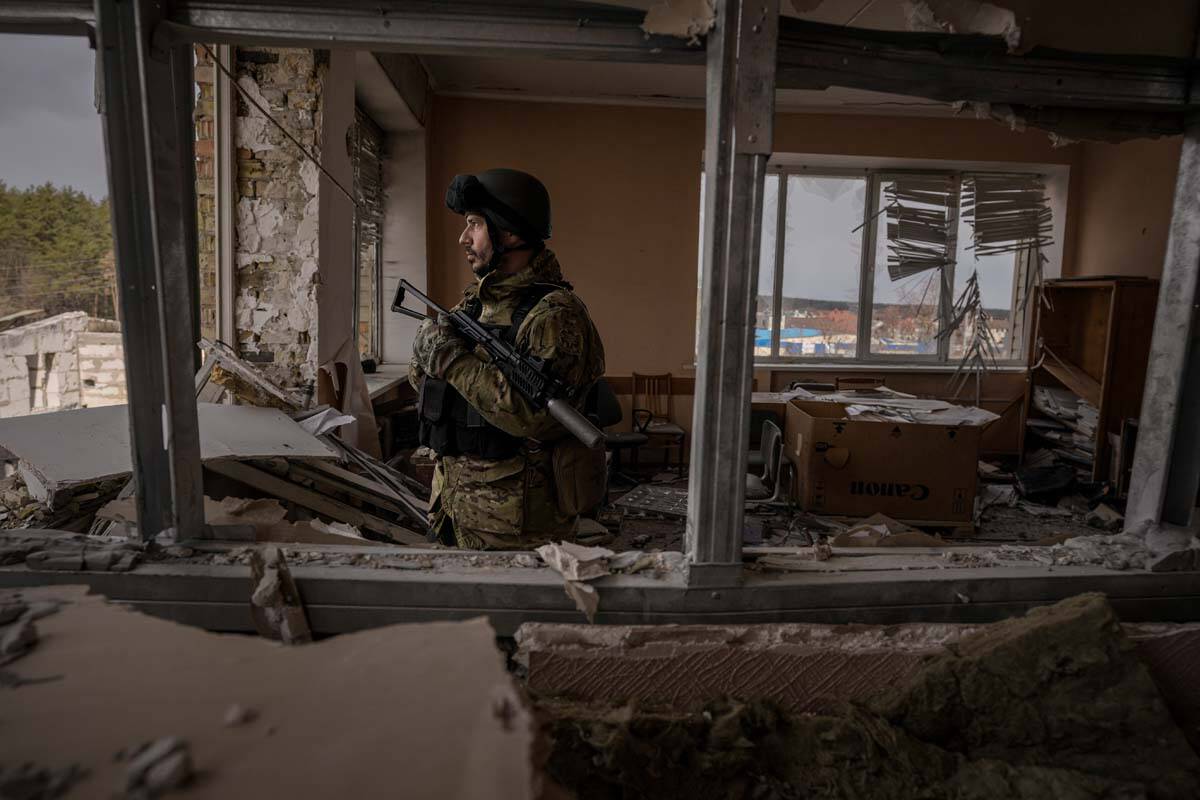 A Ukrainian serviceman stands in a heavily damaged building in Stoyanka, Ukraine, Sunday, March ...