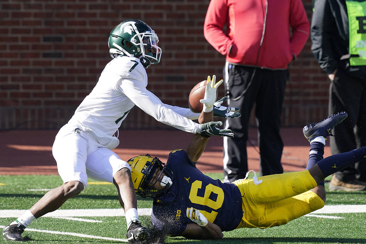 Michigan State wide receiver Ricky White (7) makes a catch while defended by Michigan defensive ...