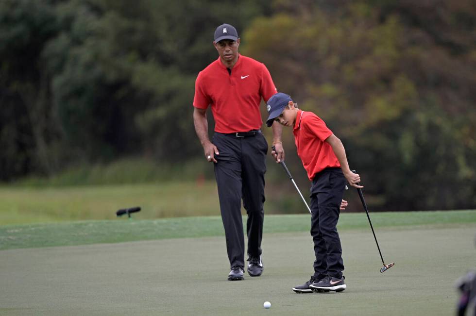 Tiger Woods watches as his son Charlie misses a putt on the 12th green during the final round o ...