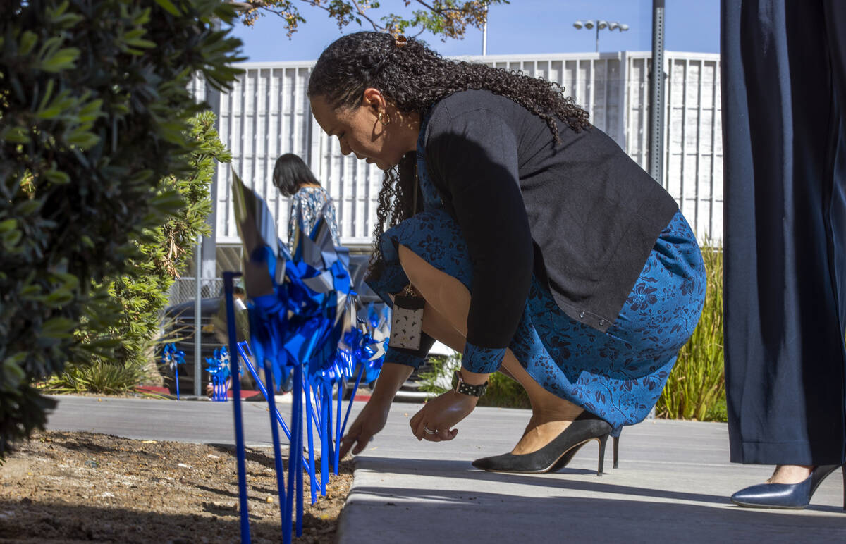 Abbie Frierson, assistant director of Clark County Family Services, plants pinwheels within the ...