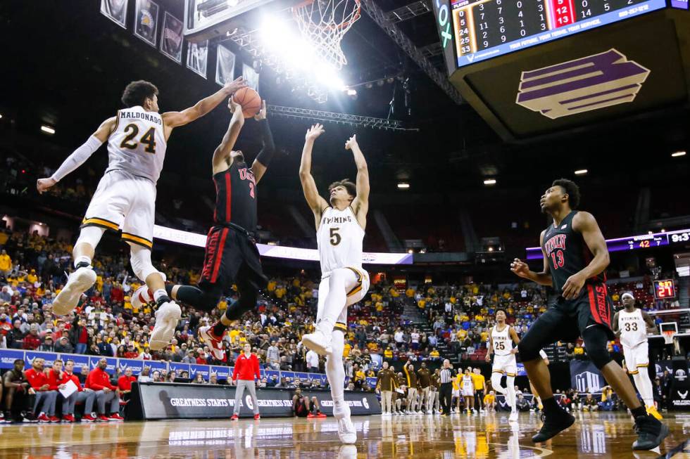 UNLV Rebels guard Justin Webster (2) attempts a layup between Wyoming Cowboys guards Hunter Mal ...