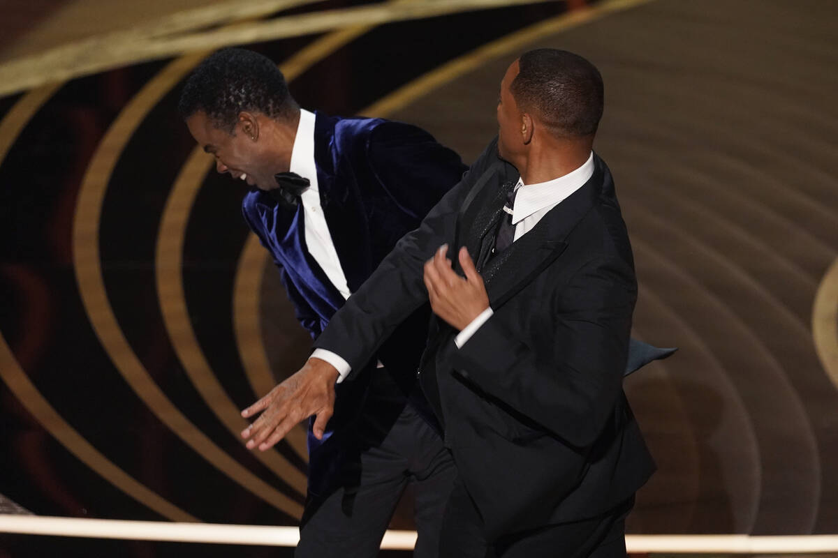 Will Smith, right, hits presenter Chris Rock on stage while presenting the award for best docum ...