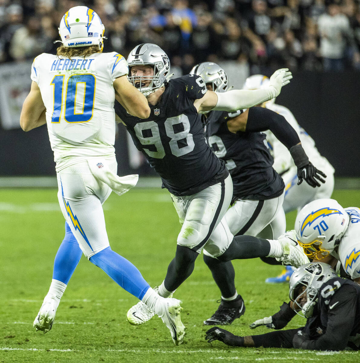 Raiders defensive end Maxx Crosby (98) closes in to sack Los Angeles Chargers quarterback Justi ...