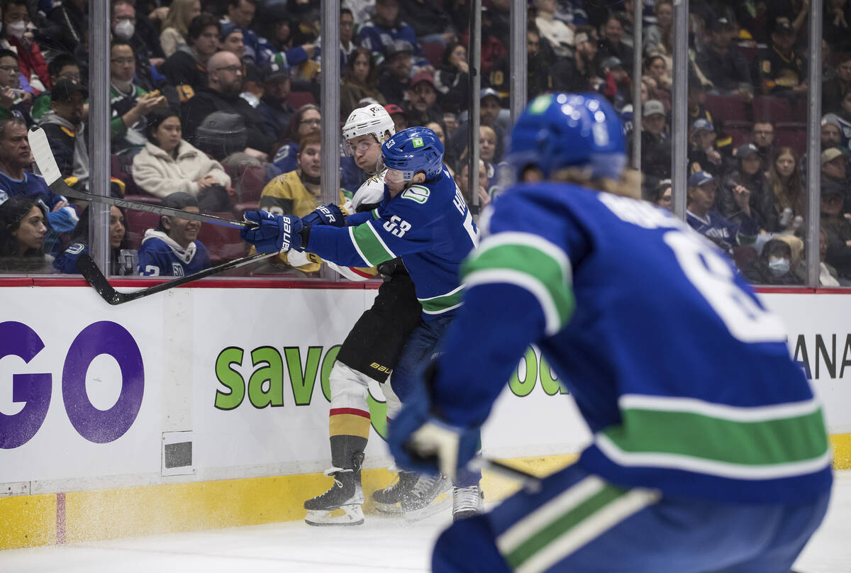 Vancouver Canucks' Bo Horvat (53) checks Vegas Golden Knights' Ben Hutton (17) during the first ...