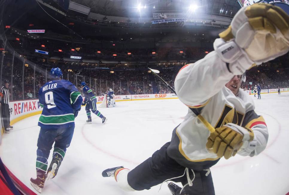 Vegas Golden Knights' Jack Eichel, right, trips and crashes into the boards while attempting to ...