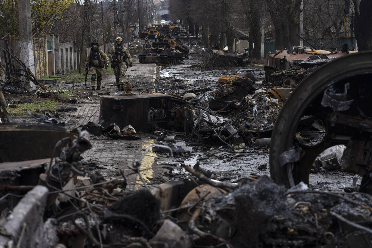 Soldiers walk amid destroyed Russian tanks in Bucha, in the outskirts of Kyiv, Ukraine, Sunday, ...