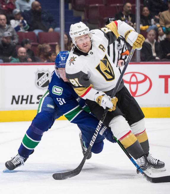 Vancouver Canucks' Tyler Myers, left, checks Vegas Golden Knights' Jonathan Marchessault during ...