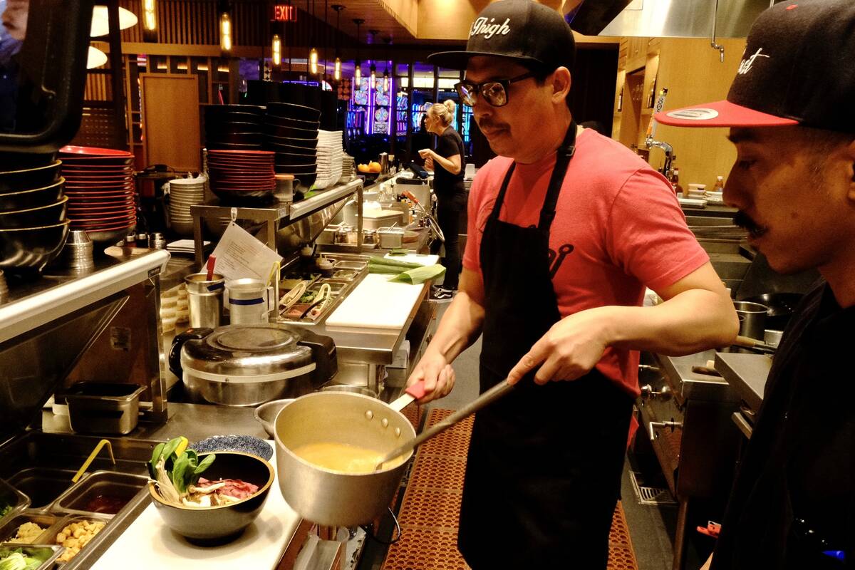 Dan Coughlin, left, chef and owner of 8 East in Circa Resort & Casino, stirs a pot of broth on ...