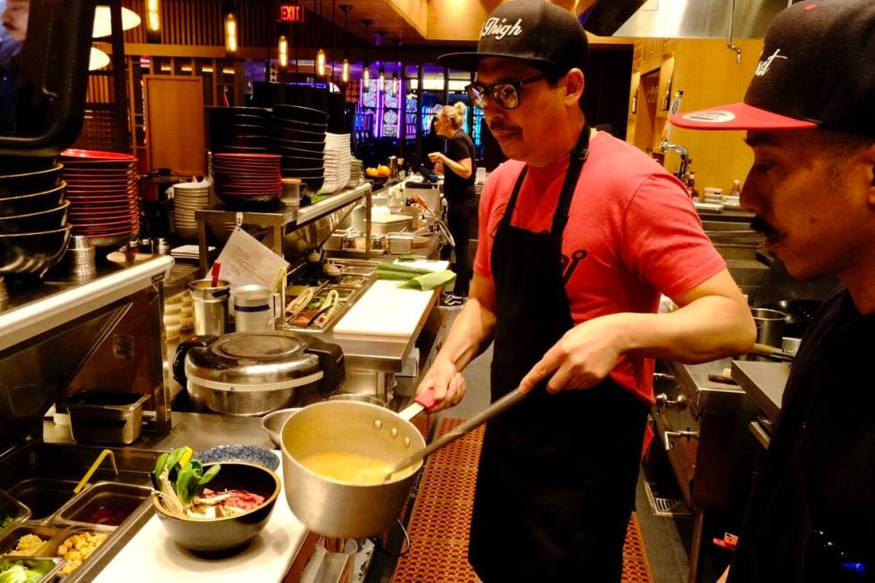 Dan Coughlin, left, chef and owner of 8 East in Circa Resort & Casino, stirs a pot of broth on ...
