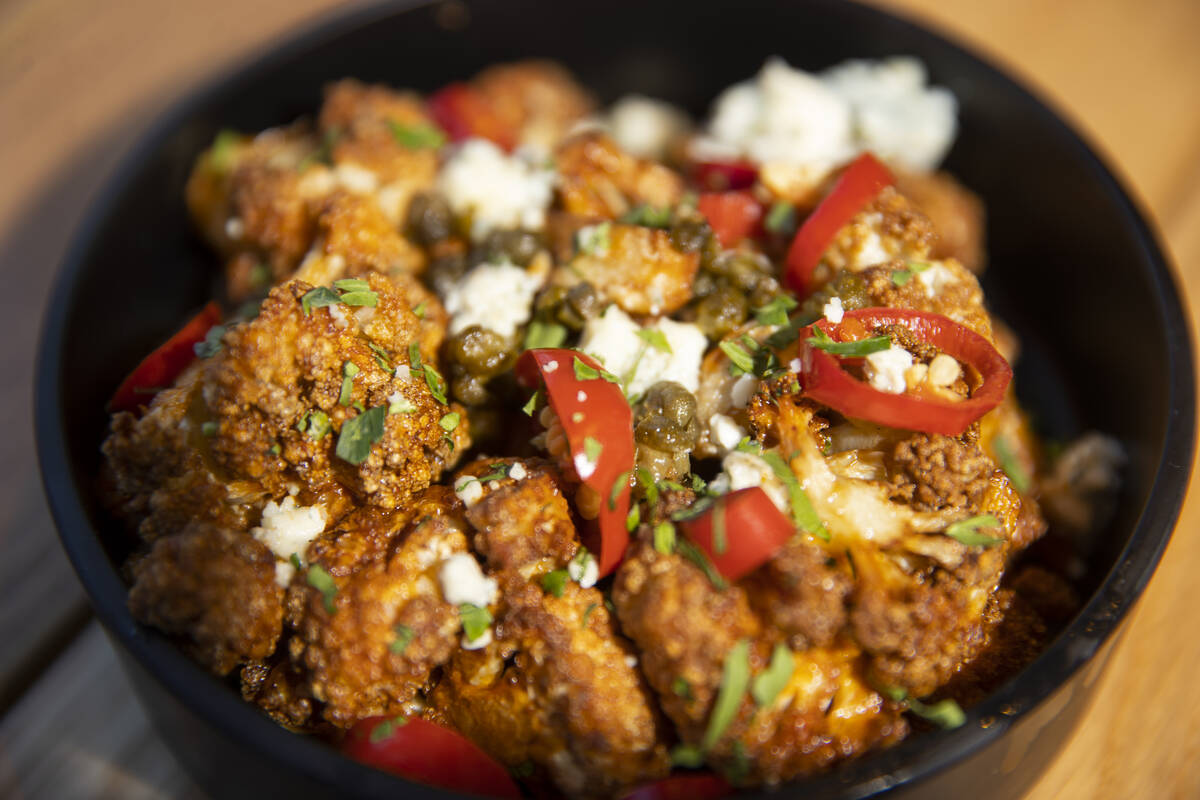The buffalo cauliflower is served with blue cheese, crispy capers, fresno chili, cilantro and r ...