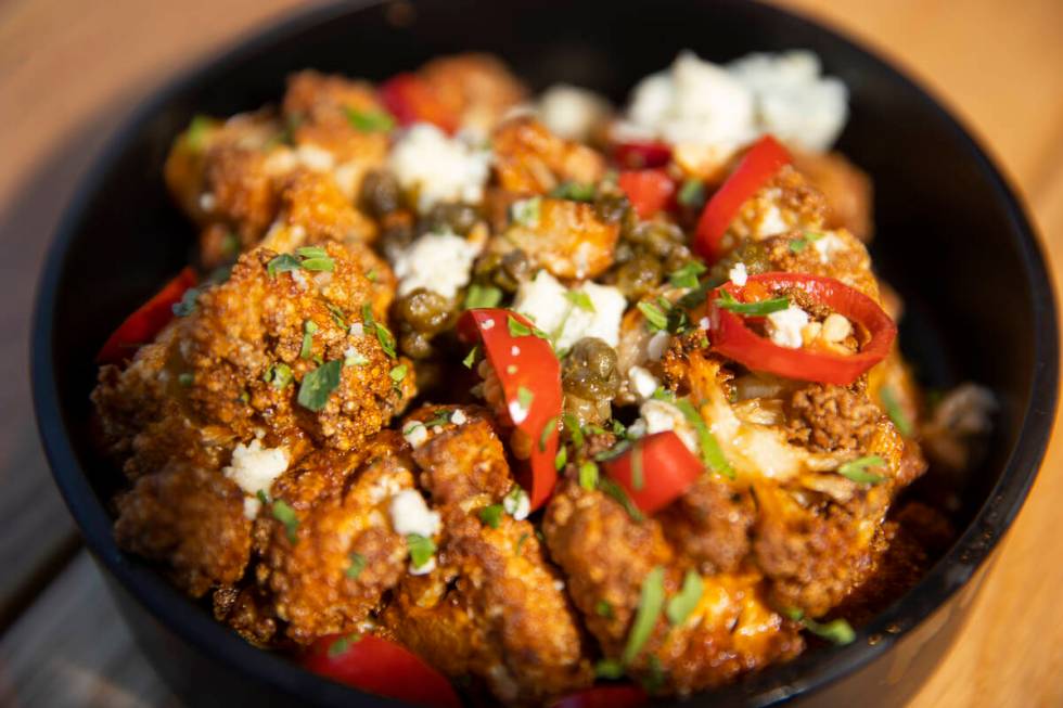 The buffalo cauliflower is served with blue cheese, crispy capers, fresno chili, cilantro and r ...