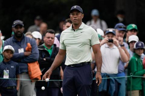 Tiger Woods drops golf balls on the driving range during a practice round for the Masters golf ...
