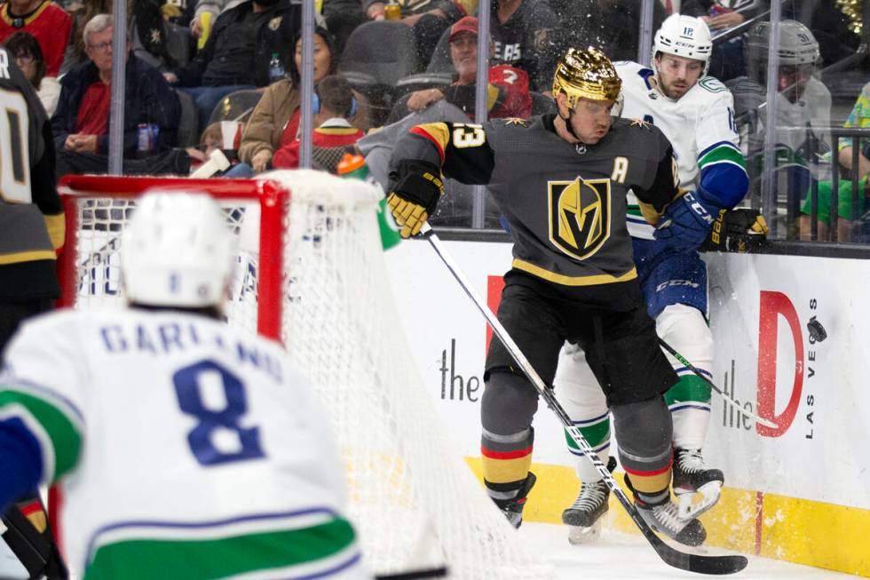 Golden Knights defenseman Alec Martinez (23) slams Canucks center Jason Dickinson (18) into the ...