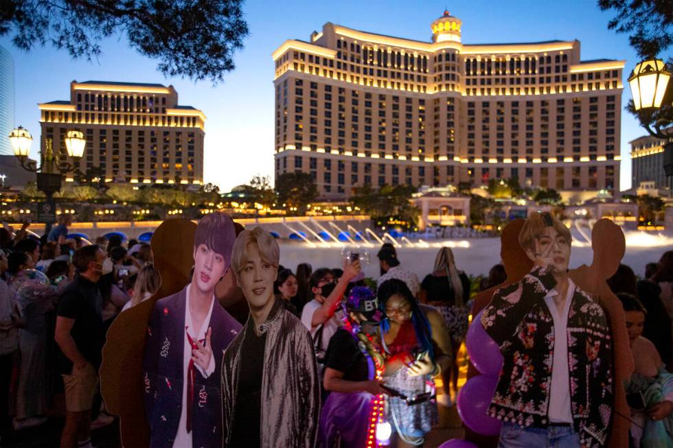Passersby photograph BTS cutouts while waiting for the Bellagio Fountain to unveil its show to ...