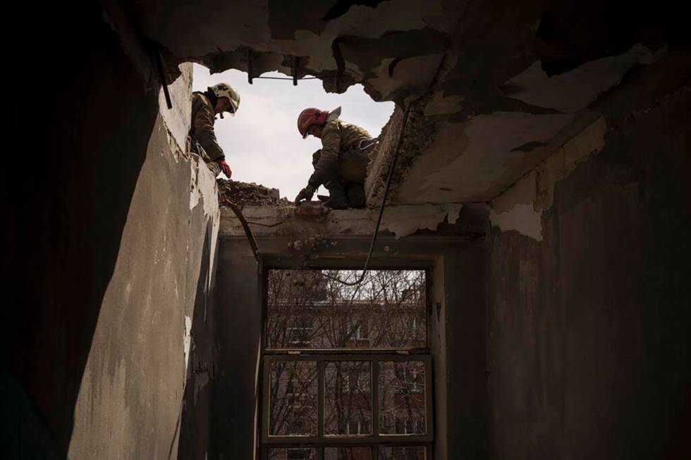Firefighters work to secure a building previously damaged by a Russian attack in Kharkiv, Ukrai ...