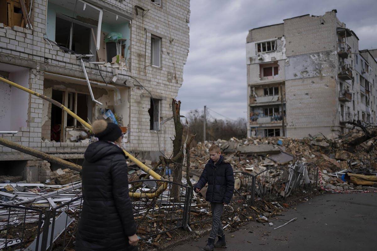 A boy is searching for his cat as he walks outside a destroyed apartment building in the town o ...