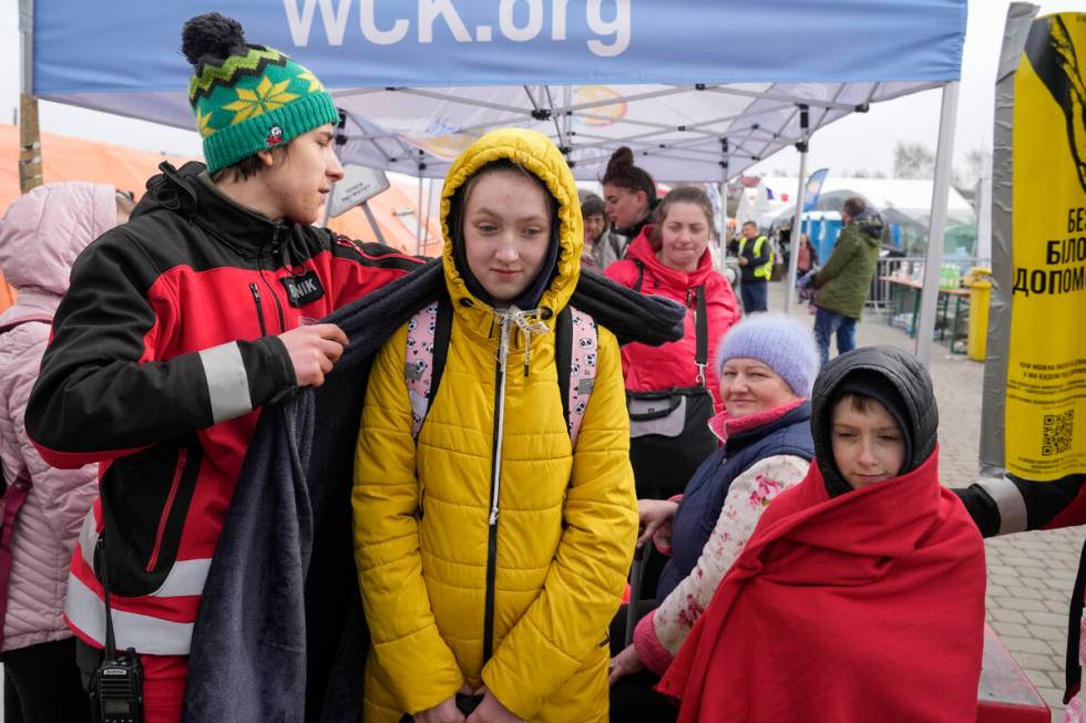 A volunteer covers a refugee with a blanket as she waits in a line after fleeing the war from n ...