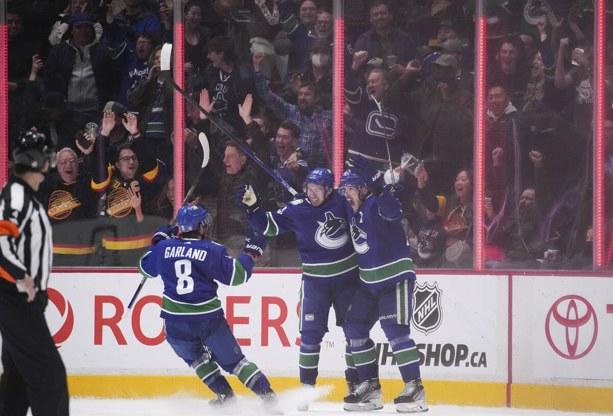 Vancouver Canucks' Conor Garland, Quinn Hughes and Bo Horvat, fromleft, celebrate Hughes' overt ...