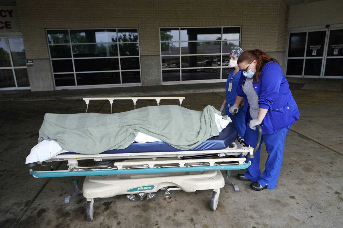 FILE - Medical staff prepare to move the body of a deceased COVID-19 patient to a funeral home ...