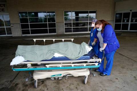 FILE - Medical staff prepare to move the body of a deceased COVID-19 patient to a funeral home ...