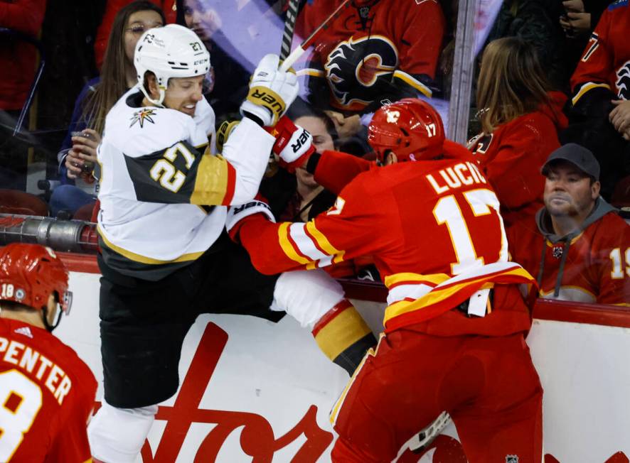 Vegas Golden Knights' Shea Theodore, left, is checked by Calgary Flames' Milan Lucic during sec ...