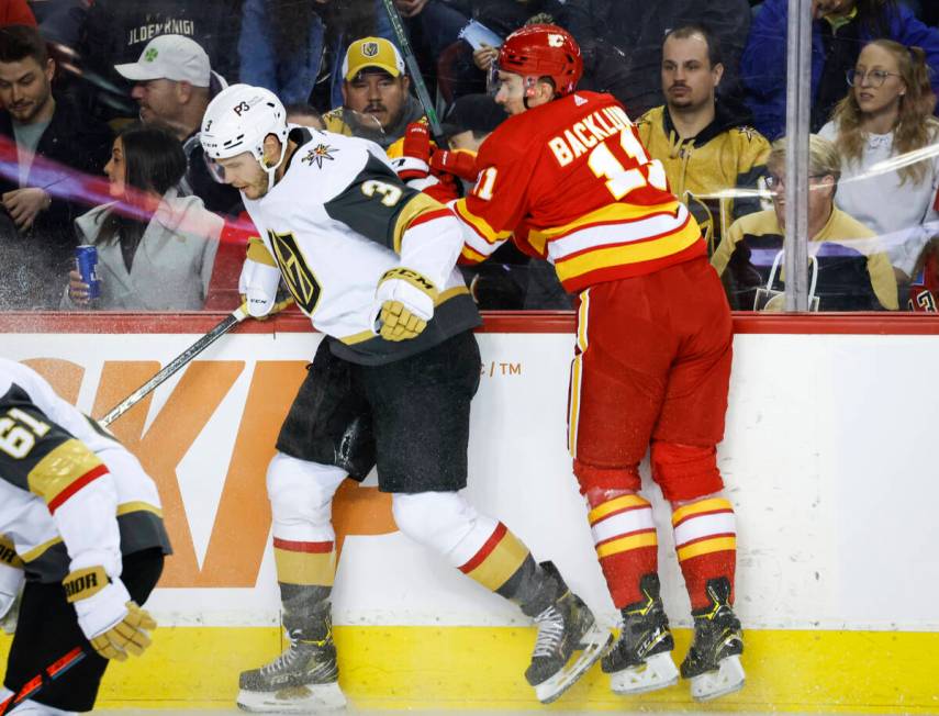 Vegas Golden Knights' Brayden McNabb, left, checks Calgary Flames' Mikael Backlund during first ...