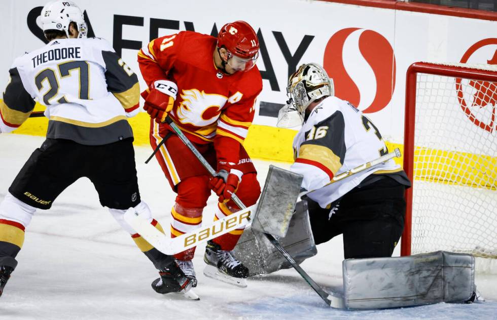 Vegas Golden Knights goalie Logan Thompson, right, tangles with Calgary Flames' Mikael Backlund ...