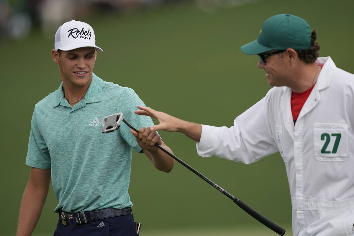 Amateur Aaron Jarvis, of the Cayman Islands, hands his putter to his caddie AJ McInerney after ...