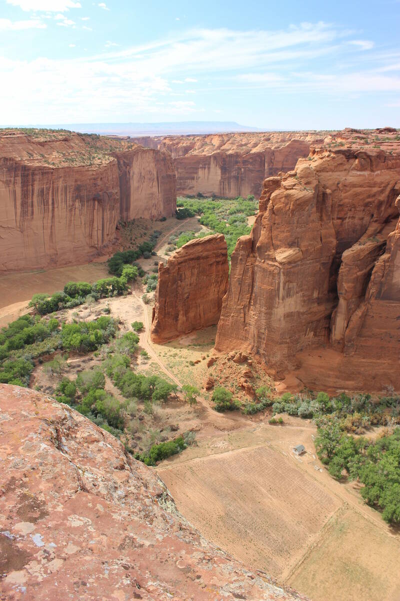The steep red sandstone cliffs rise one thousand feet off the fertile farmland of the canyons b ...