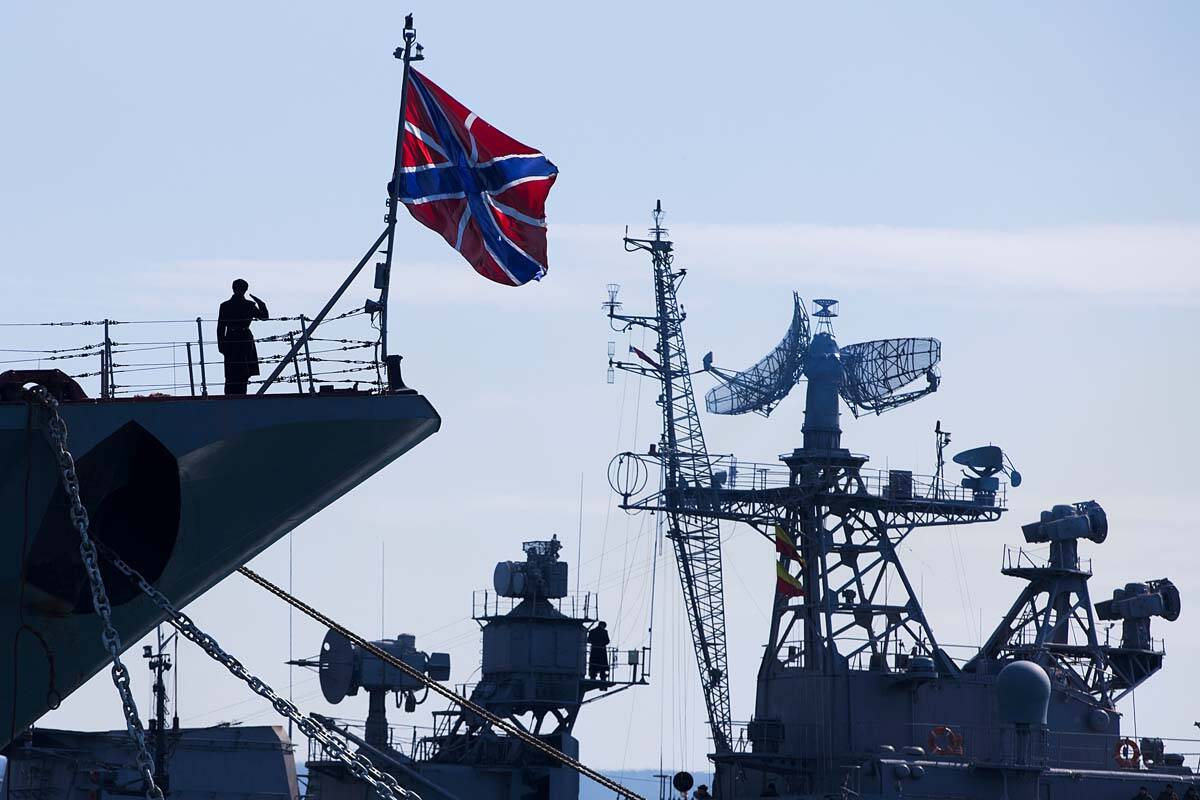 A Russian sailor salutes on the bow of Missile Cruiser Moskva, left, as crew of Russian patrol ...
