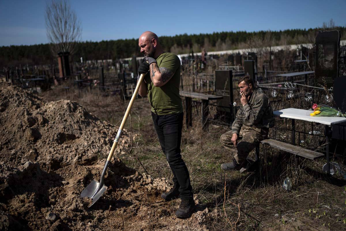 Cemetery worker Vladislav, left, takes a break from working at the funeral of Tetyana Gramushny ...