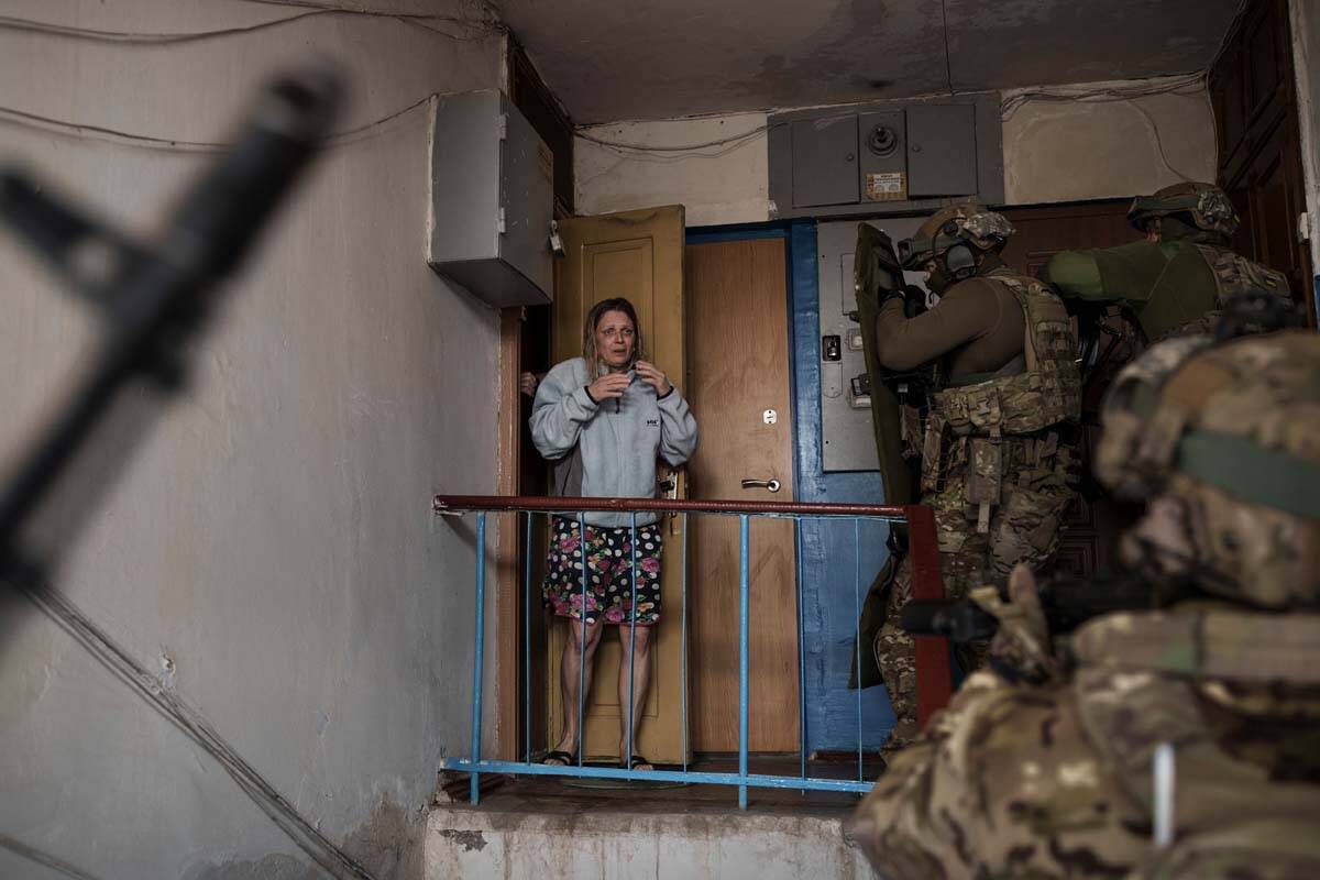 A woman looks as Security Service of Ukraine (SBU) servicemen enter a building during an operat ...