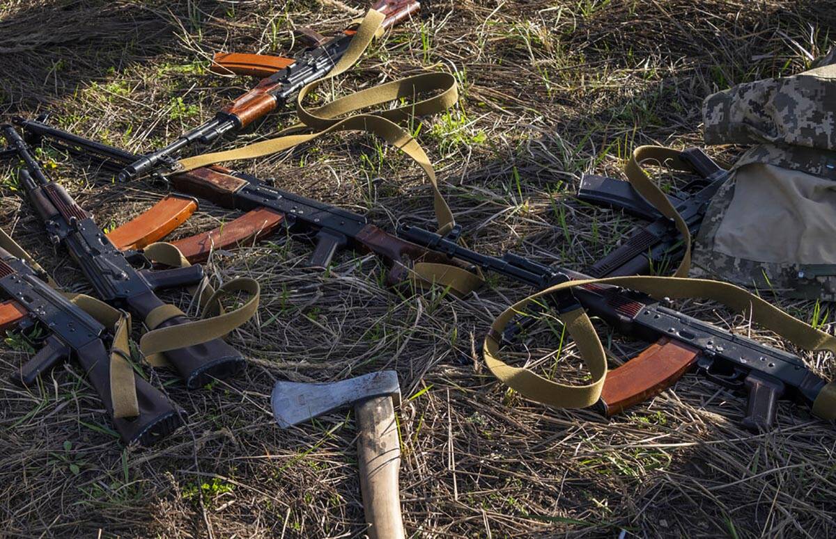 Rifles and an axe lay in a field where Ukrainian soldiers dig a trench in case of another Russi ...