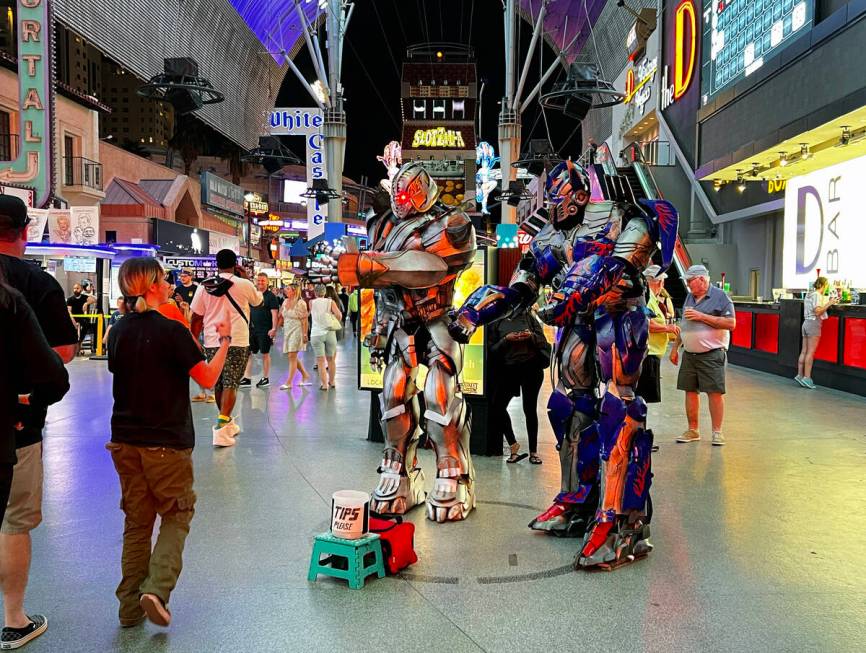 Street performers as Transformers greet a visitor as they pose for photos within a designated c ...