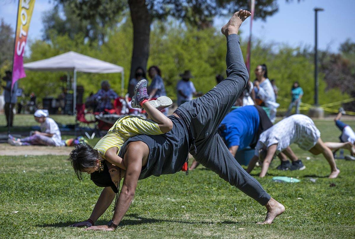 Tony Thipdavong does a yoga move with his daughter Addy, 4, helping out on top during a class a ...