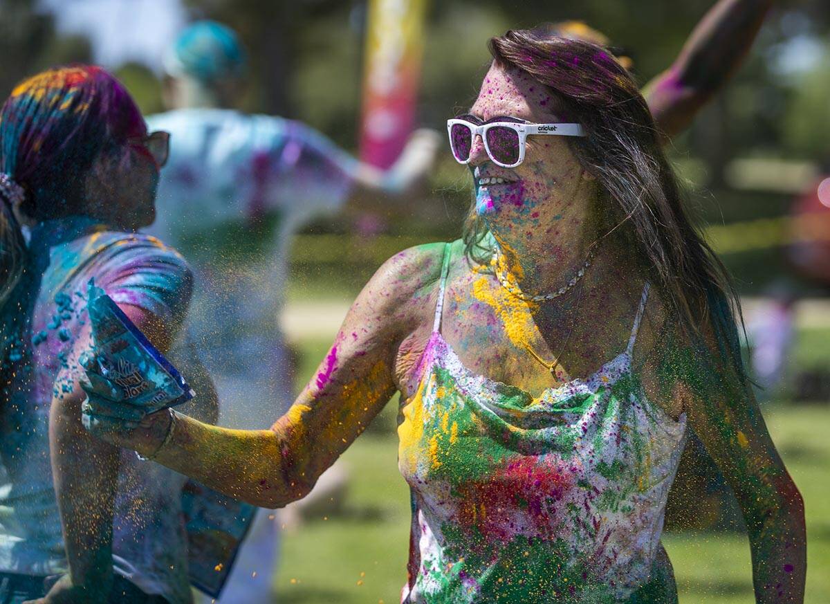 Donna Turner of Yuma, Arizona, throws some color on friends as the music plays during the Holi ...