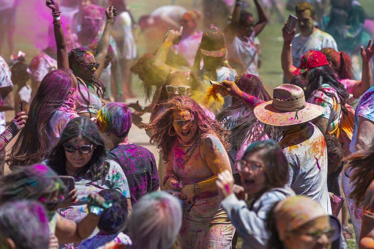 Participants throw colors together as the music continues during the Holi Festival of Colors at ...