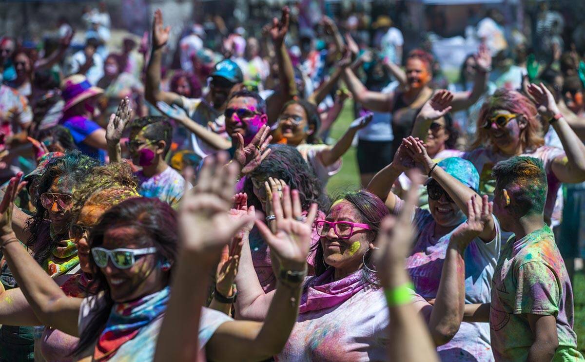 Participants follow a dancer on stage during the Holi Festival of Colors which features music, ...
