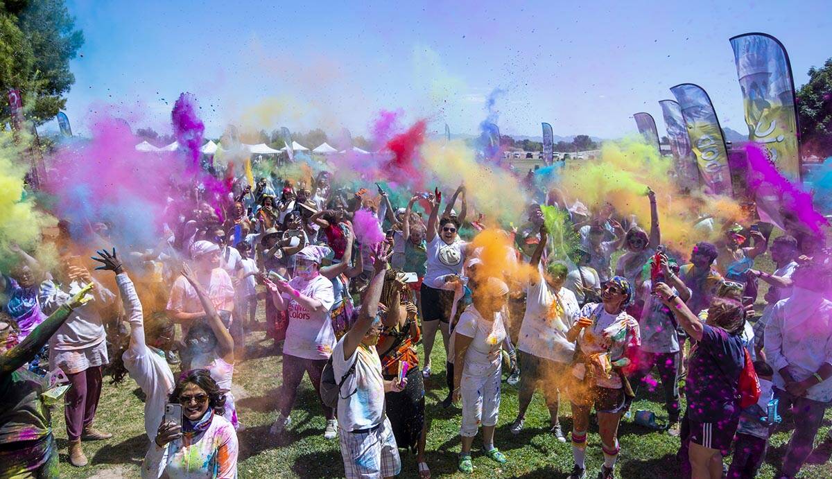 Participants throw colors together as the music continues during the Holi Festival of Colors at ...