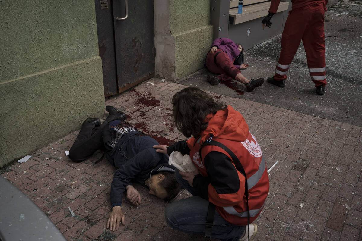 Emergency workers help injured civilians during a Russian bombardment in Kharkiv, Ukraine, Sund ...