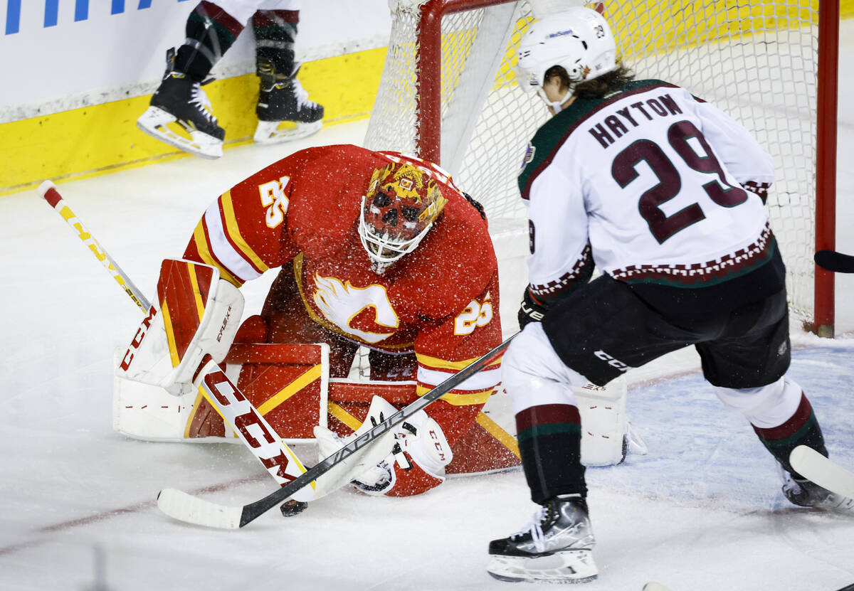 Arizona Coyotes' Barrett Hayton, right, tries for the puck as Calgary Flames goalie Jacob Marks ...