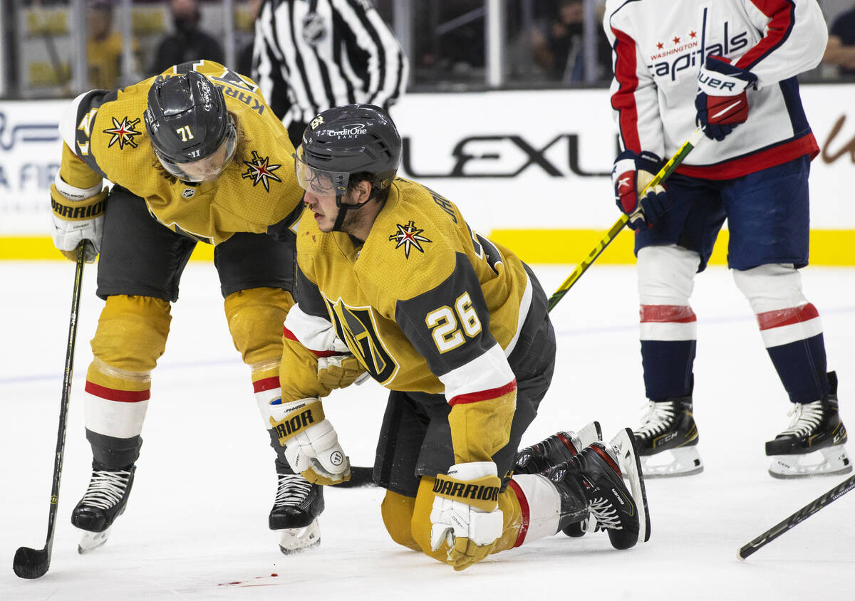 Golden Knights center Mattias Janmark (26) is helped to his feet by Golden Knights center Willi ...