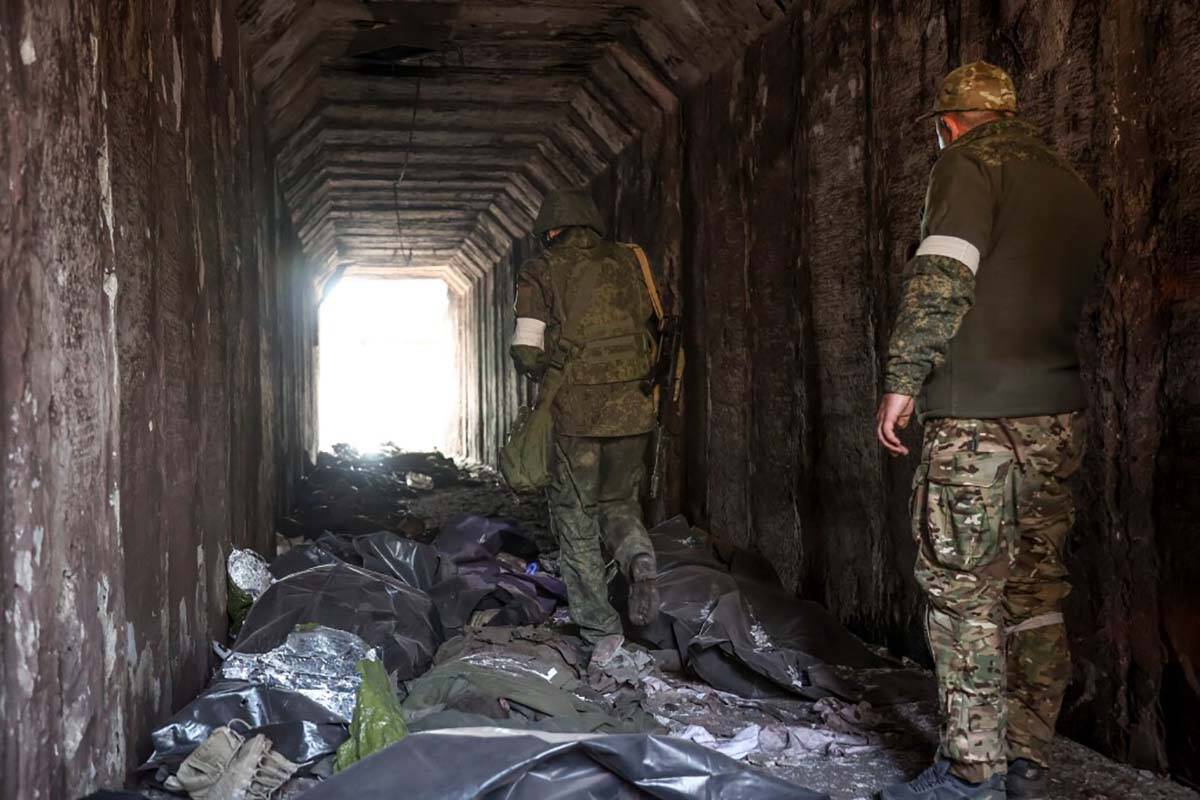 Servicemen of the Donetsk People's Republic militia look at bodies of Ukrainian soldiers placed ...