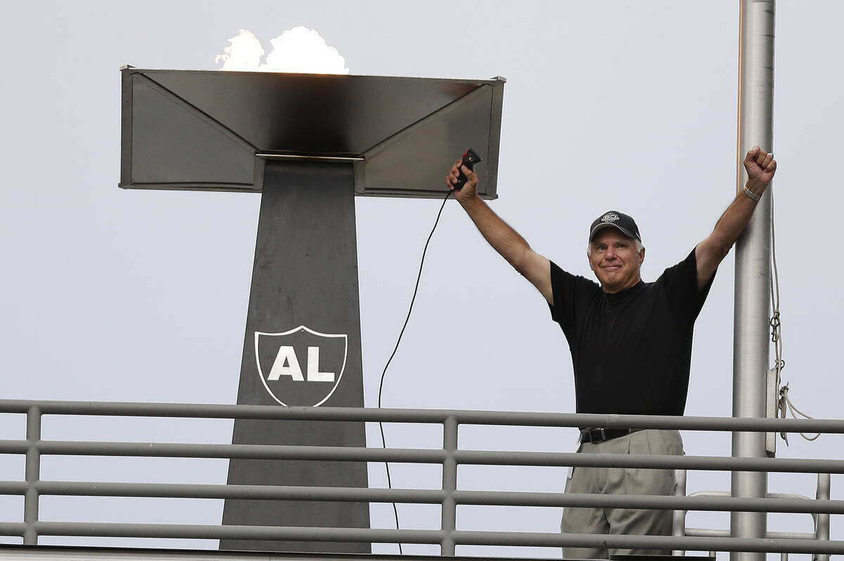 Former Oakland Raiders quarterback Daryle Lamonica raises his arms after lighting a torch for f ...