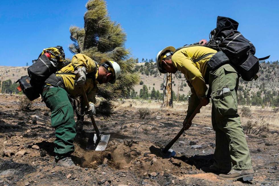 Two firefighters monitor hot spots from a wildfire burning on the outskirts of Flagstaff, Ariz. ...