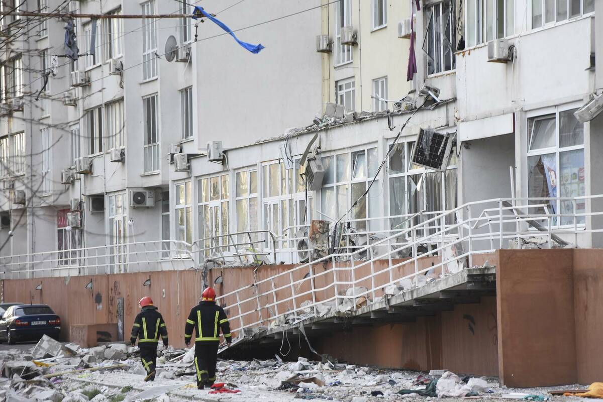 Firefighters walk past an apartment building damaged by Russian shelling in Odesa, Ukraine, Sat ...