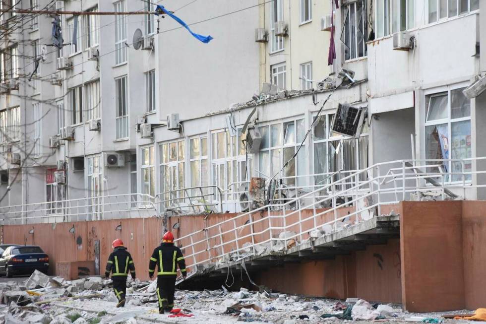 Firefighters walk past an apartment building damaged by Russian shelling in Odesa, Ukraine, Sat ...